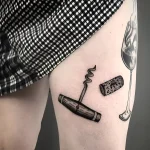 Черно-белая татуировка штопора и пробки на бедре, выполненная в реалистичном стиле.