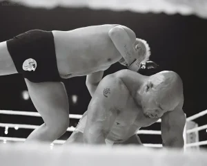 Двейн Джонсон в черно-белом кадре из фильма «The Smashing Machine», борющийся на ринге, с видимой татуировкой на плече.