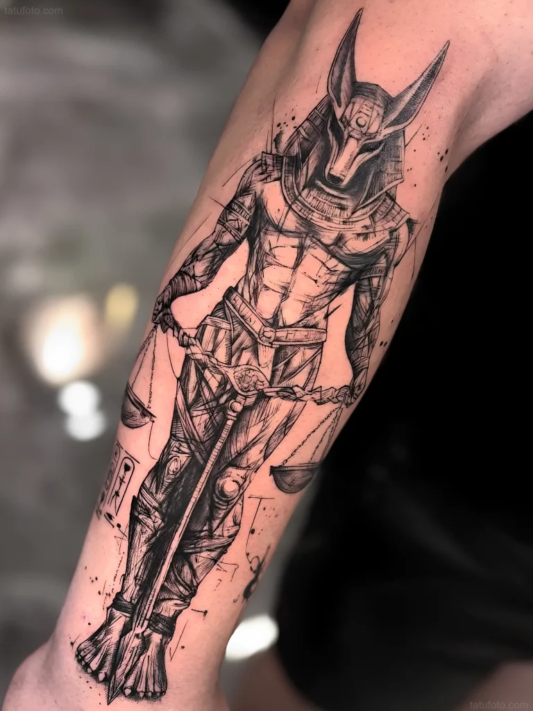Tatuaje de Anubis estilo Sketch sosteniendo la balanza de la justicia, en el antebrazo