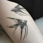 Черно-белая татуировка двух скалярий на бедре, выполненная в реалистичной графике с акцентом на плавники и текстуру.