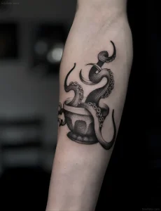 Черно-белая татуировка на руке: чашка, из которой выползает осьминог, выполненная в технике дотворк.