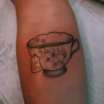Черно-белая татуировка чашки с белыми цветами и биркой Earl Grey на руке