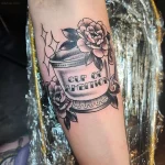 Черно-белая татуировка чашки кофе с цветами пионов и надписью 'CUP OF AMBITION' на руке