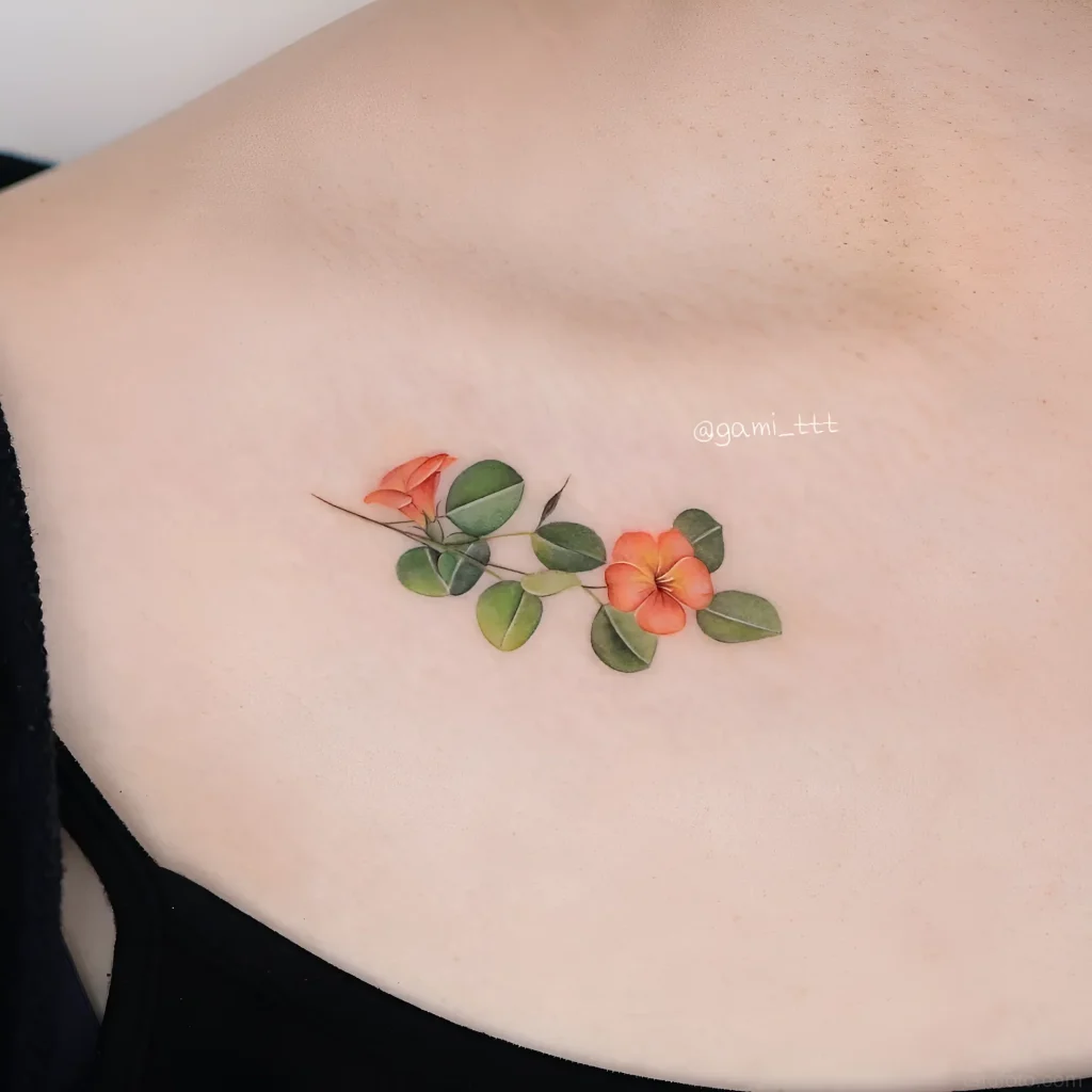 锁骨上的柔和水彩桉树纹身，带有橙色花朵和绿色叶子