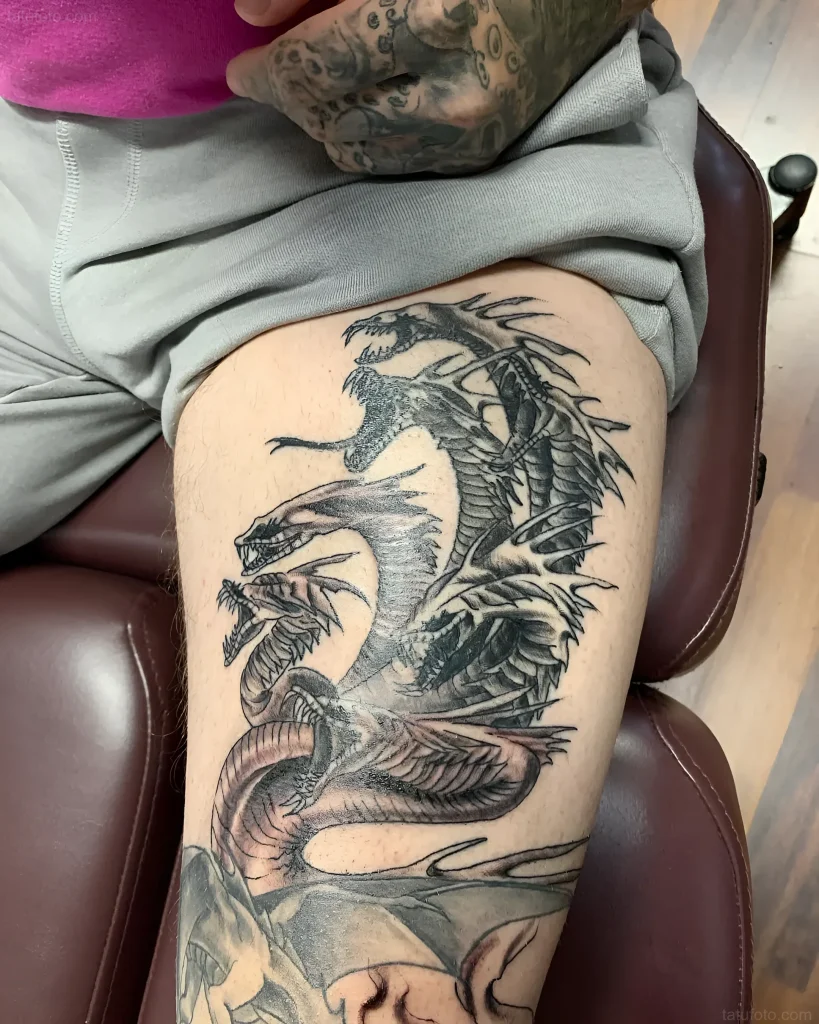 Tattoo of a multi-headed Hydra in black and gray style on the thigh, demonstrating the power and complexity of the mythological creature