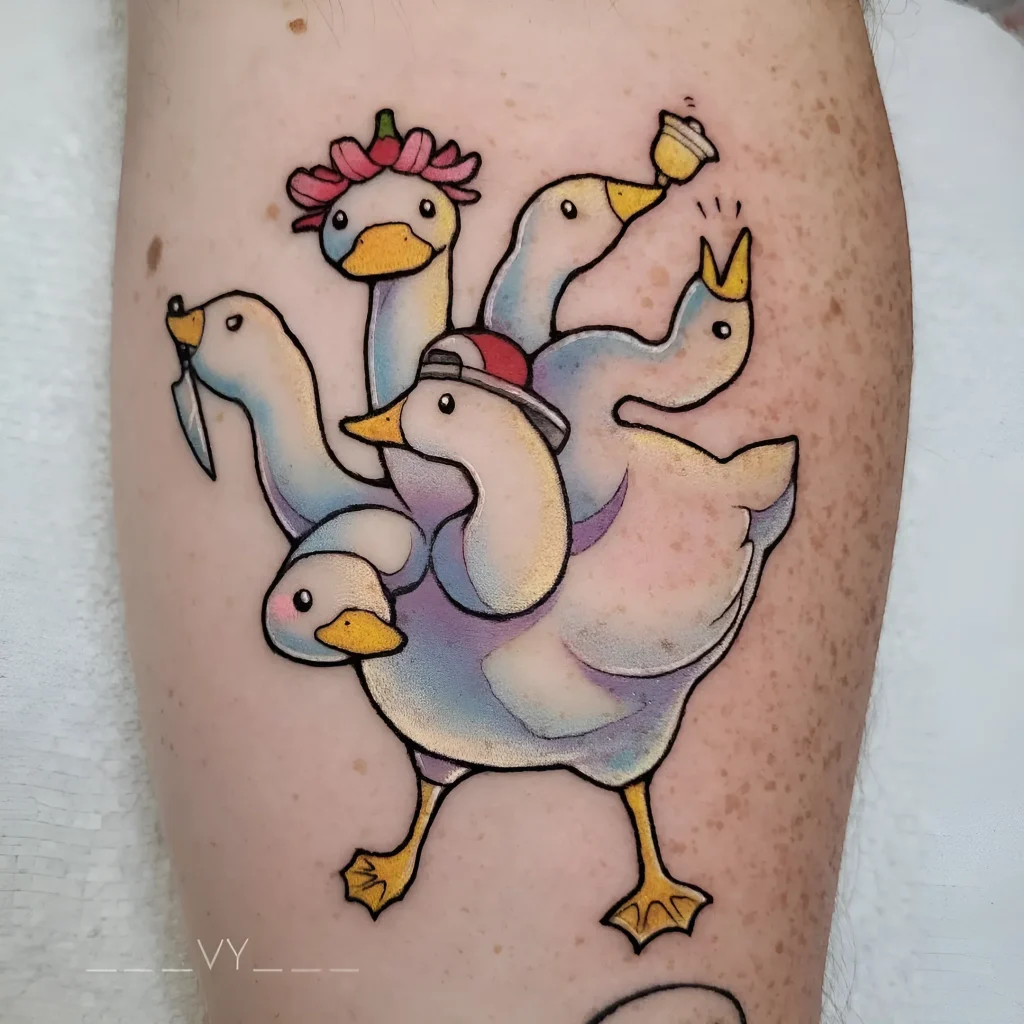 Bright tattoo of a multi-headed goose with a knife, crown, and flower, done in new school style