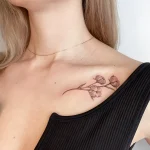 Элегантная татуировка веточки хлопка на ключице, выполненная в минималистичном стиле