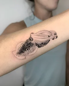 Черно-белая татуировка кальмара на предплечье, выполненная в технике dotwork с детализированной проработкой текстуры.