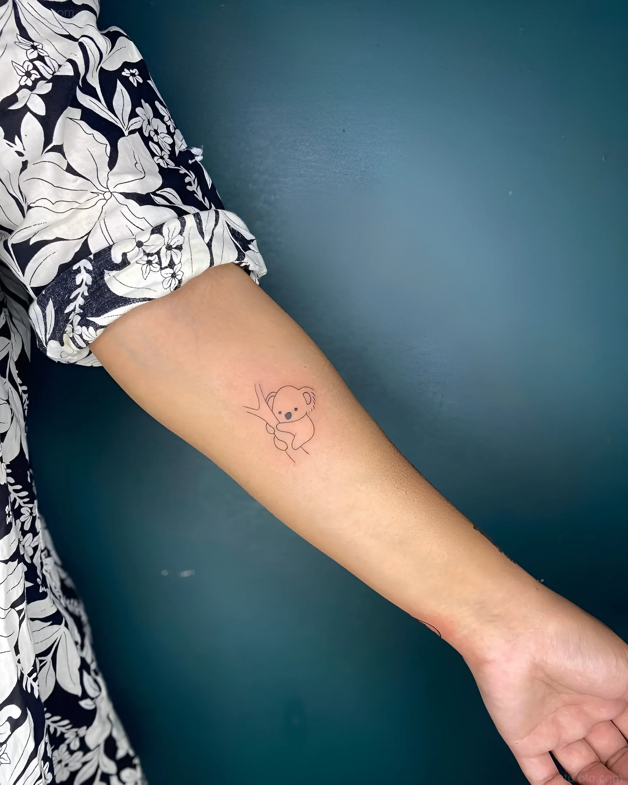 Photo of a tattoo: a contour image of a koala sitting on a branch, on the inner forearm
