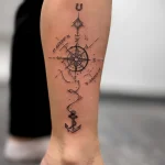 Вертикальная татуировка на голени с компасом, GPS координатами, якорем и подковой в стиле лайнворк