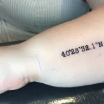 Минималистичная татуировка с географическими координатами на предплечье