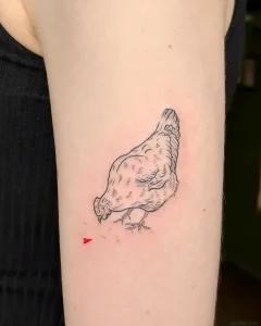 Минималистичная татуировка курицы в графичном стиле с небольшим красным сердцем под клювом на руке