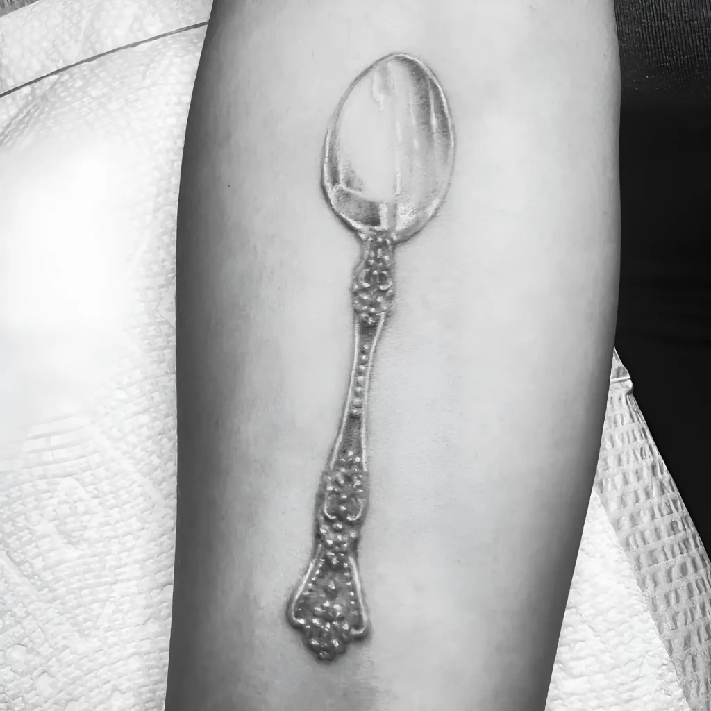 Schwarz-weißes realistisches Tattoo eines antiken Silberlöffels am Arm
