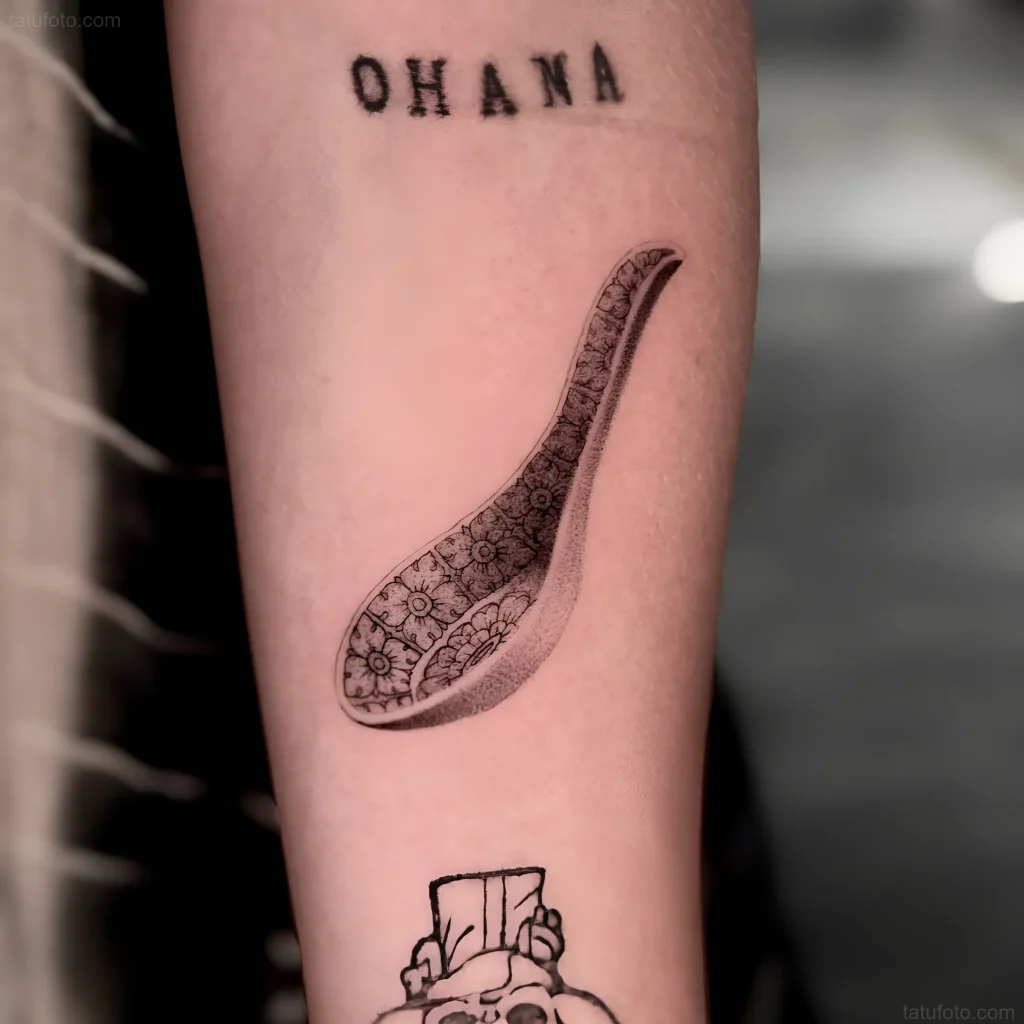 Schwarz-weißes Löffel-Tattoo mit Blumenmuster am Unterarm, das Wohlstand und Familienwerte symbolisiert.