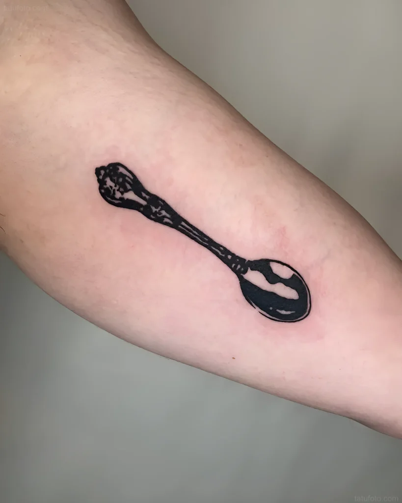 Schwarz-weißes Löffel-Tattoo am Bizeps, minimalistisches Design