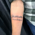 Минималистичная татуировка на предплечье с фразой 'The end is the beginning' на санскрите и английском