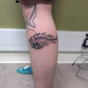 Черно-белая татуировка рыбы-удильщика на голени, выполненная в технике дотворк с элементами штриховки.
