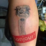 Фото татуировки страуса на голени с французской надписью 'Bonjour!' в стиле реализм.