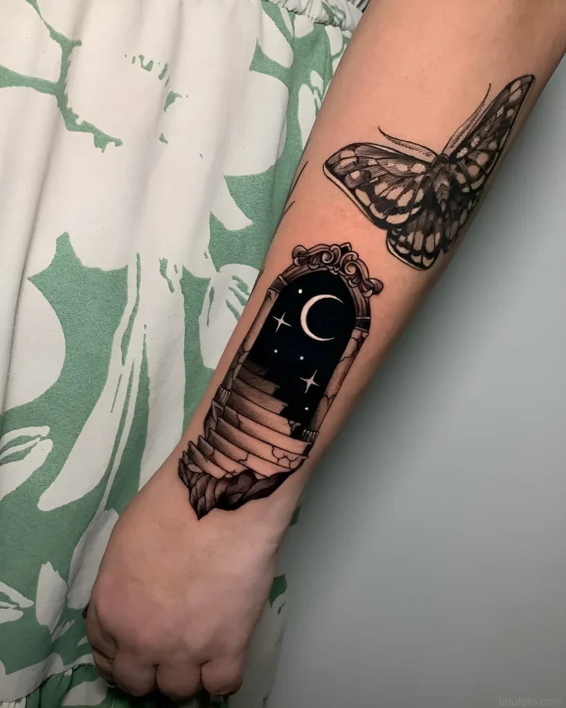 Tattoo of a portal with a staircase leading to a night sky with a moon and stars, next to an image of a moth