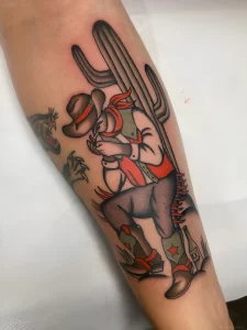 Тату в стиле олдскул: Ковбой, прикуривающий сигарету на фоне гигантского кактуса