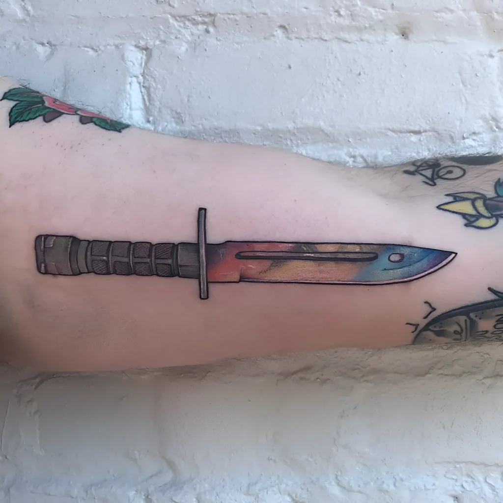Tatouage de baïonnette avec un dégradé de rouge à bleu sur l'avant-bras