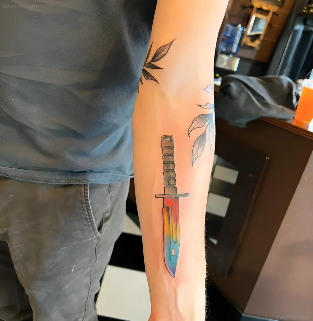 Tatouage de baïonnette avec un dégradé de couleurs arc-en-ciel sur l'avant-bras