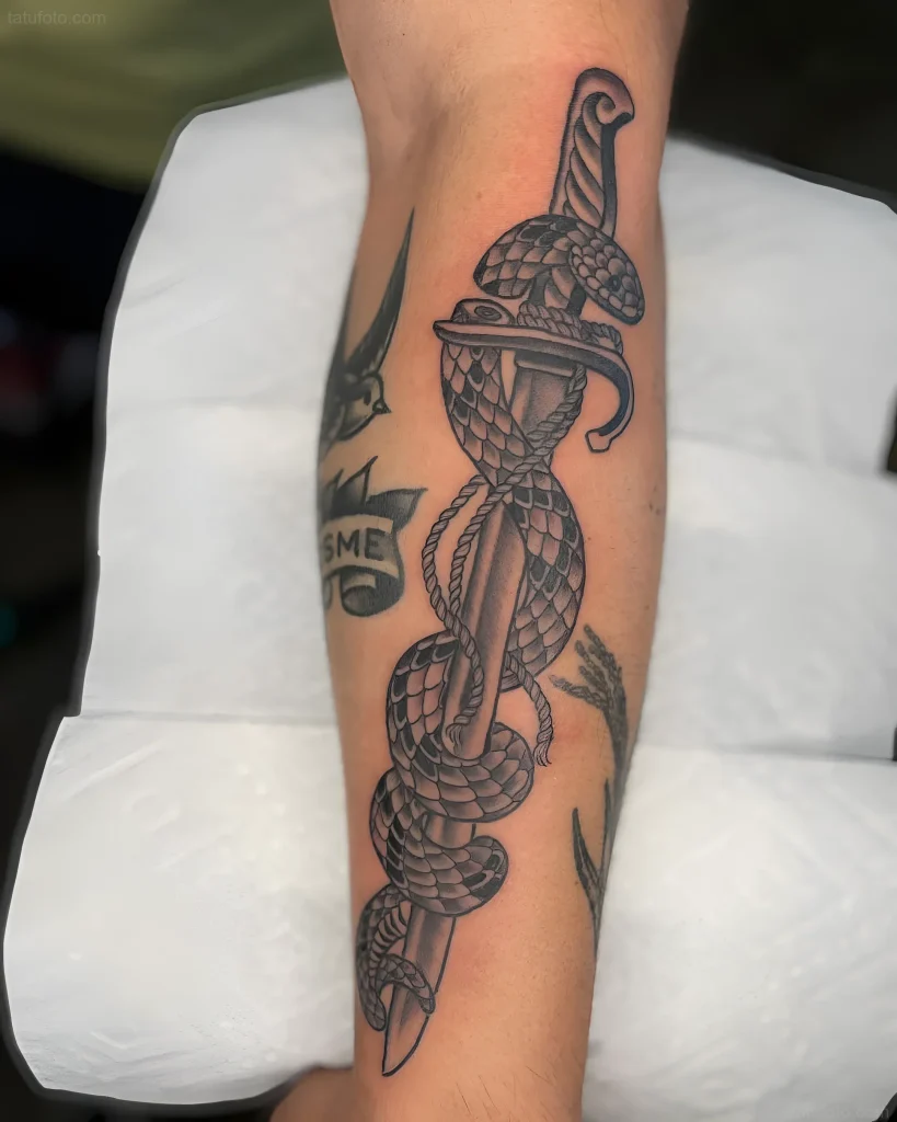 Tatouage de baïonnette enroulée d'un serpent, en noir et gris, démontrant force et transformation.