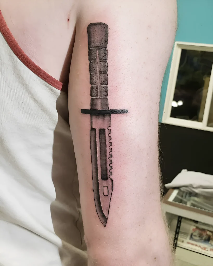 Tatouage de baïonnette sur l'avant-bras, réalisé dans une technique réaliste