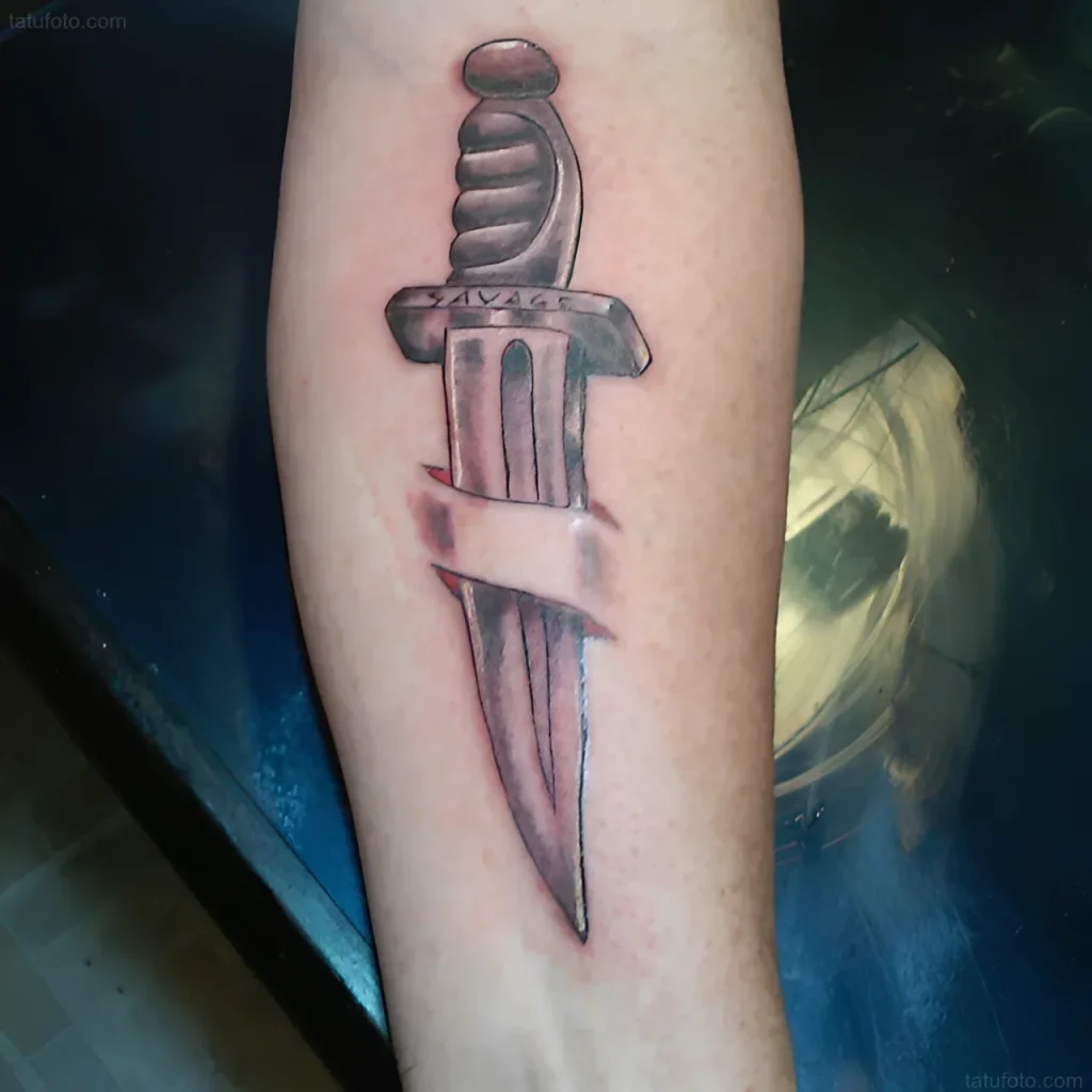 Tatouage de baïonnette transperçant la peau, avec l'inscription SAVAGE