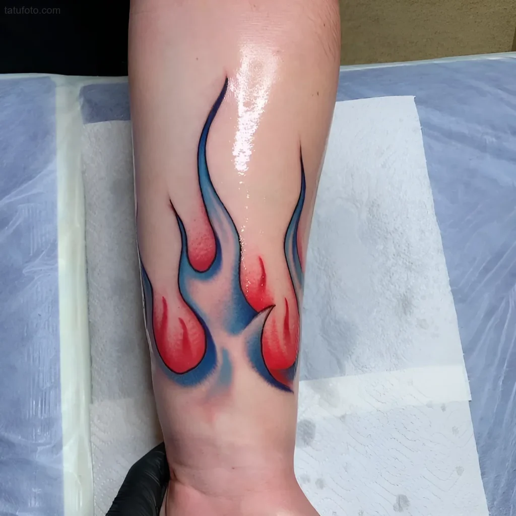 Tatuaje de fuego eterno en el antebrazo con lenguas de fuego rojas y azules