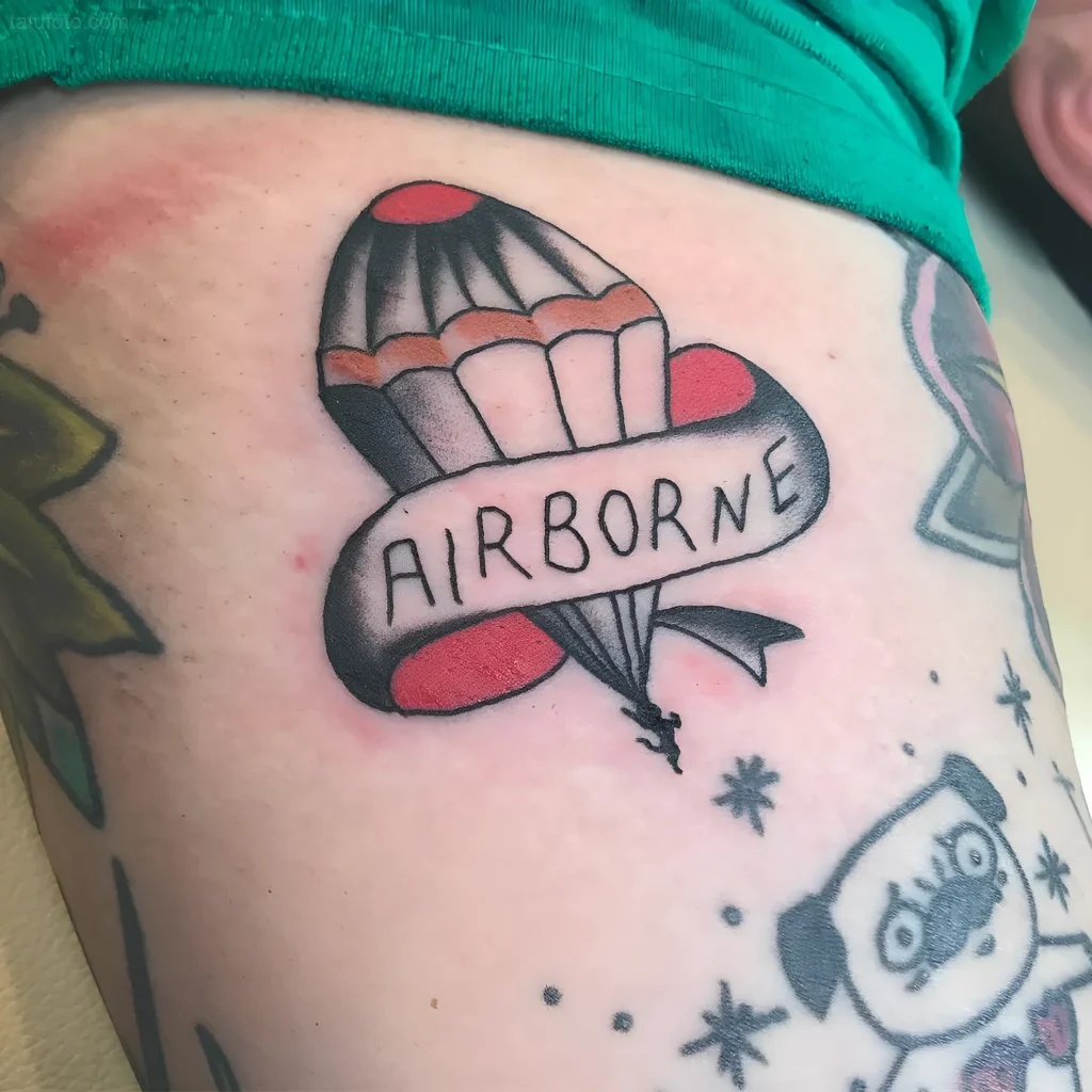 老派风格的降落伞纹身,带有'AIRBORNE'绶带和伞兵剪影,展示了空降兵(VDV)纹身的意义
