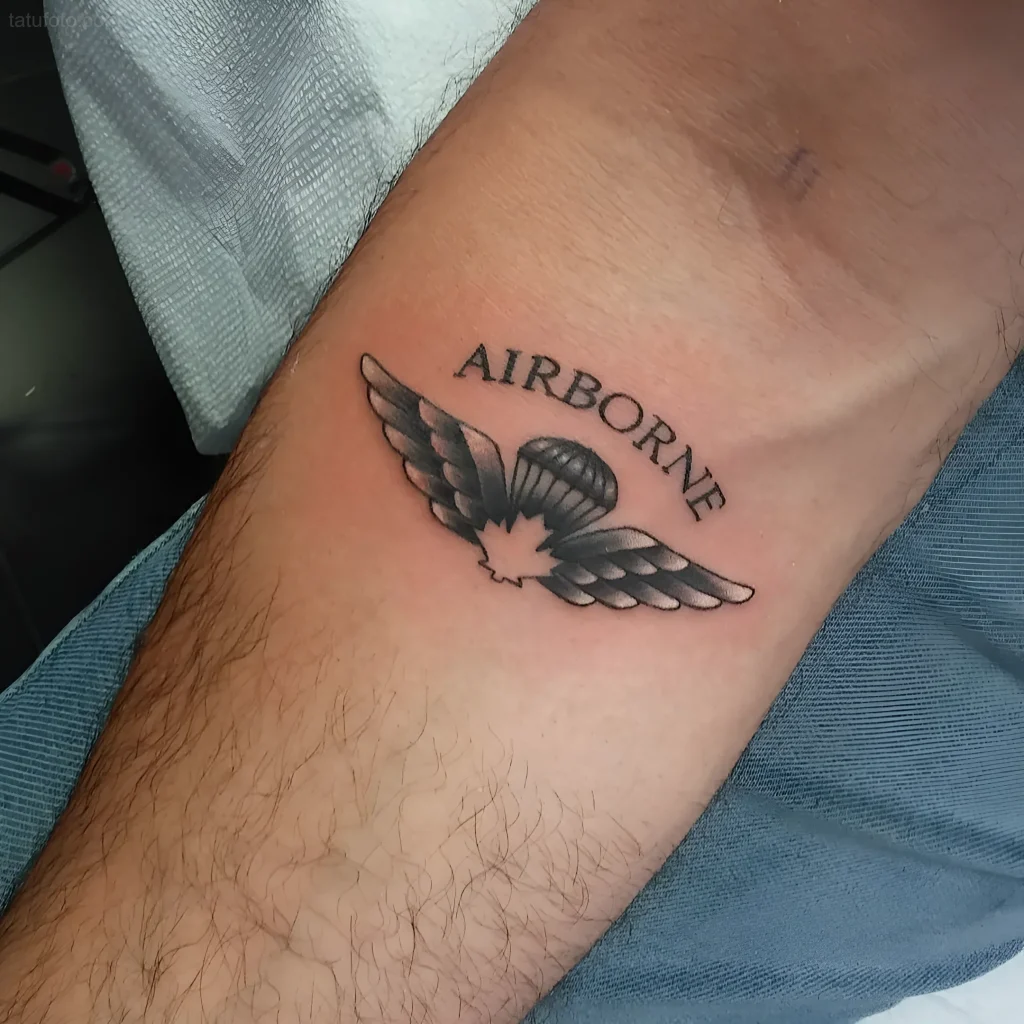 अग्रबाहु पर 'Airborne' लिखा पैराशूट और पंखों वाला वीडीवी टैटू