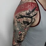 Татуировка на плече с изображением самолета, парашютов и надписи AIRBORNE, символизирующая службу в ВДВ.