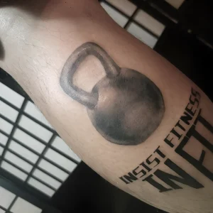 Реалистичная татуировка гири на предплечье с надписью "INSIST FITNESS"