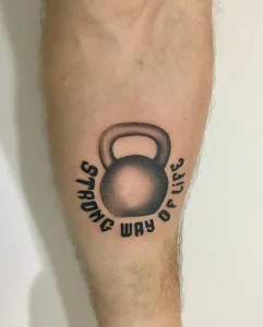 Татуировка гири с надписью "STRONG WAY OF LIFE" на предплечье
