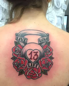 Татуировка гиря с розами и надписями 'LIVE', 'LOVE', 'LIFT', символизирующая физическую силу и жизненную философию.