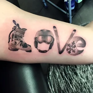 Татуировка в виде слова 'LOVE', где вместо букв изображены лыжный ботинок, шлем с очками, лыжная палка и снежинка
