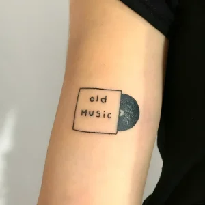Минималистичная татуировка виниловой пластинки с надписью 'old Music' на руке