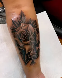 Татуировка с изображением шахматной королевы, стоящей среди лепестков розы, на фоне шахматной доски.