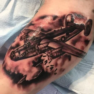Татуировка бомбардировщика B-24 Liberator с надписью "Jolly Roger" и сбрасываемыми бомбами, выполненная в стиле реализма с элементами акварели.