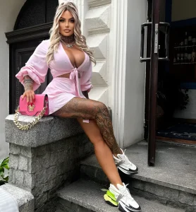Женщина с объемными татуировками на ногах, сидящая на ступенях