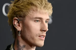 Machine Gun Kelly в профиль, демонстрируя татуировки на ухе и пирсинг в носу.