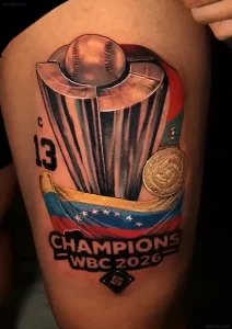 Крупный план татуировки на бедре Сальвадора Переса, изображающей кубок WBC, бейсбольный мяч, флаг Венесуэлы и надпись 'Champions WBC 2026'.