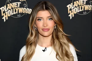 Сами Шин, дочь Чарли Шина и Дениз Ричардс, позирует на фоне логотипа Planet Hollywood, демонстрируя свои светлые волосы и серьги-кольца.