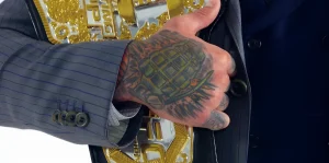 Рука бойца UFC Коди Гарбрандта с татуировкой гранаты, придерживающая чемпионский пояс