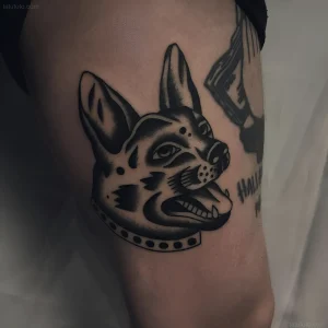Тату немецкой овчарки в стиле олд скул, выполненное черными чернилами, с детальной проработкой морды и ошейника.