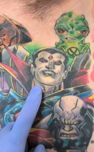 Детальный снимок части тела с множеством ярких татуировок персонажей Marvel, включая Мистера Синистера и Грута, сделанный в новостном репортаже.