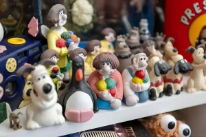 Коллекция фигурок Wallace & Gromit, включая Уоллеса, Громита и других персонажей, выставлена на полке.