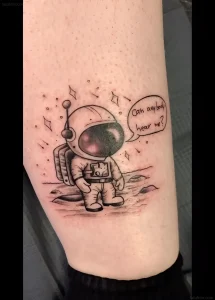 Татуировка милого космонавта на поверхности планеты, произносящего фразу 'Can anybody hear me?'