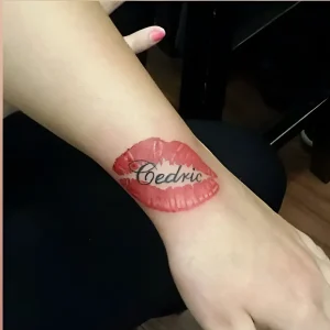 Татуировка в виде красных губ с именем 'Cedric' на запястье